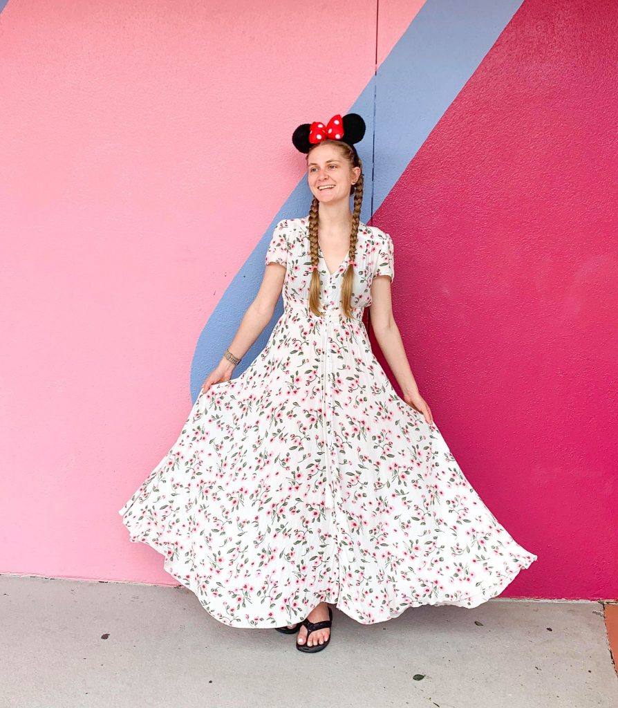 woman in dress and minnie ears in front of pink wall - disney packing list