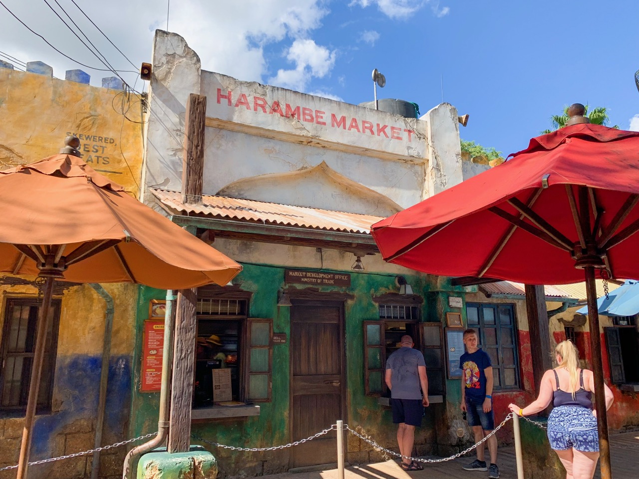 colorful umbrellas and people ordering at a window Animal Kingdom quick service