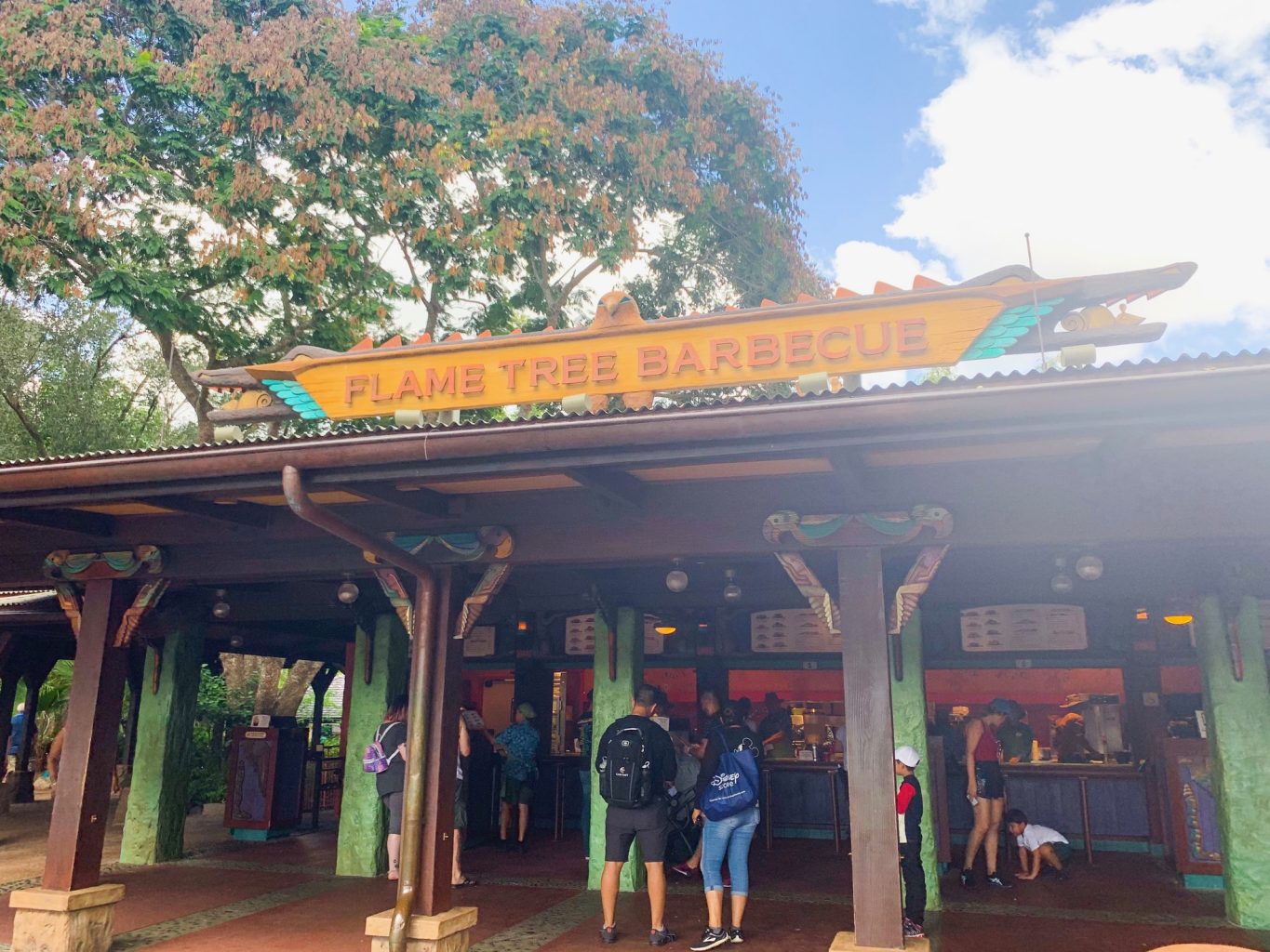 The outdoor ordering area of Palm Tree Barbecue features a  bright orange sign, and is one of the best Animal Kingdom restaurants for BBQ and quick service!