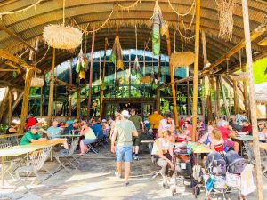 outdoor dining area made of wood and straw with wooden and straw decorations hanging from ceiling