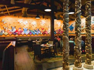 intricately carved totem poles in front of bright wall background Disney restaurants