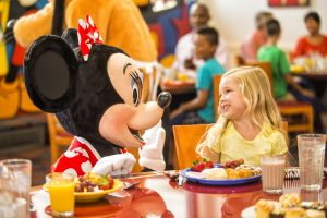 Minnie and little girl sitting side by side and smiling at each other