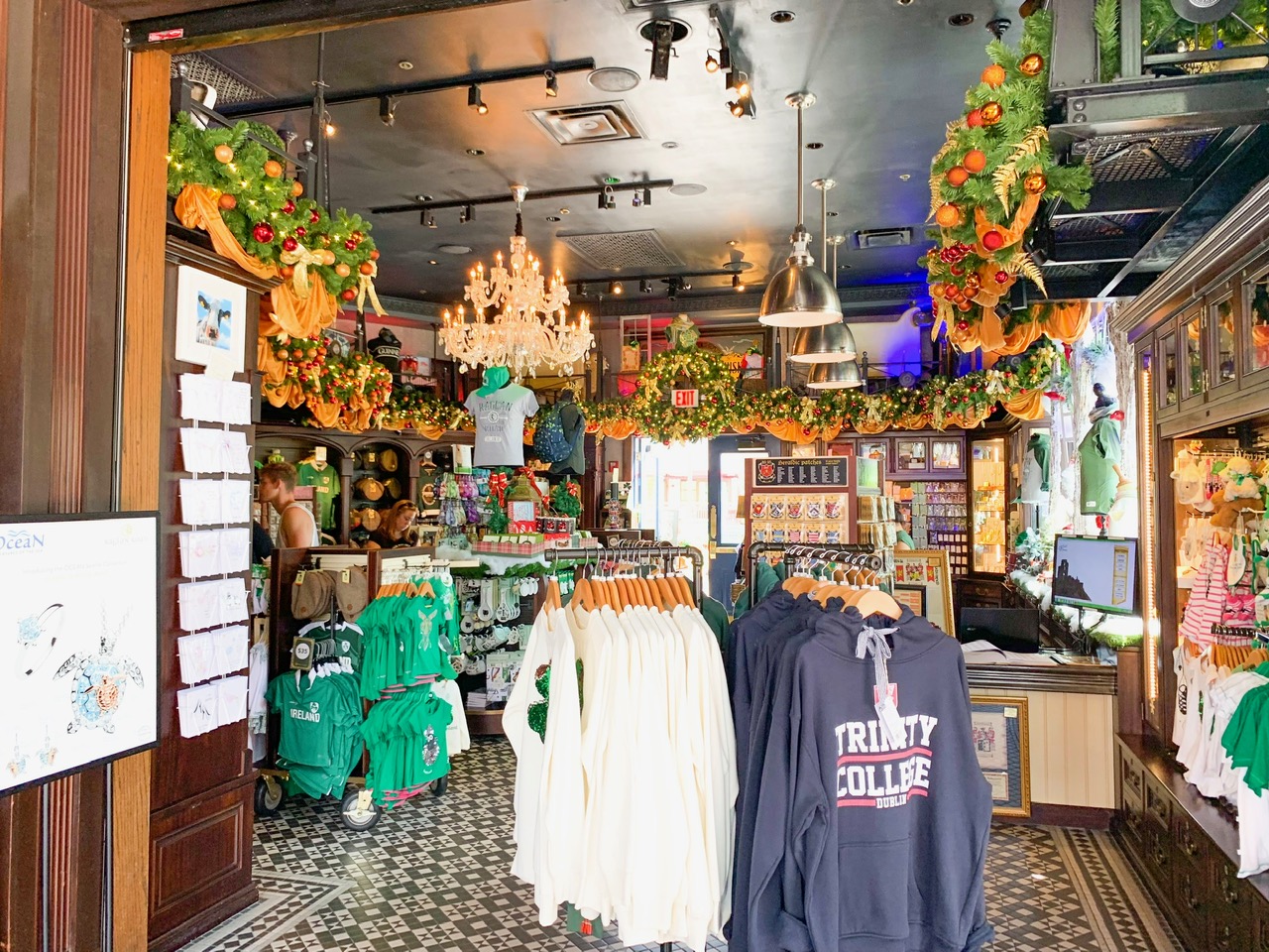 Inside of Shop for Ireland at Disney Springs with displays of clothing in the foreground, including a navy Trinity college sweatshirt and green childrens t shirts in the background. 