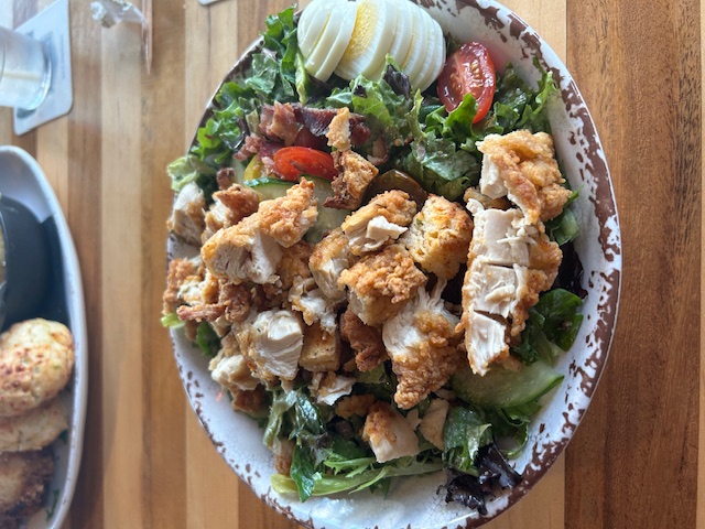 large salad with fried chicken and eggs on it
