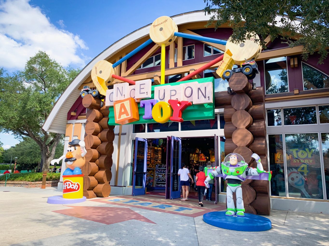 Storefront of Once Upon a Toy at Disney Springs. The storefront is decorated like a log cabin, with Mr. Potato head sitting on a container of Play-Doh on the left side and Buzz Lightyear on the right side. The words "Once Upon" are in scrabble tiles, the "A" looks like a toy block, and "Toy" is made up of toy alphabets in blue, yellow, and red respectively. 