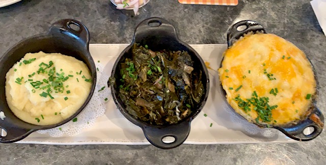 mashed potatoes, greens, and mac and cheese in black dishes on a plate at homecomin best disney restaurant