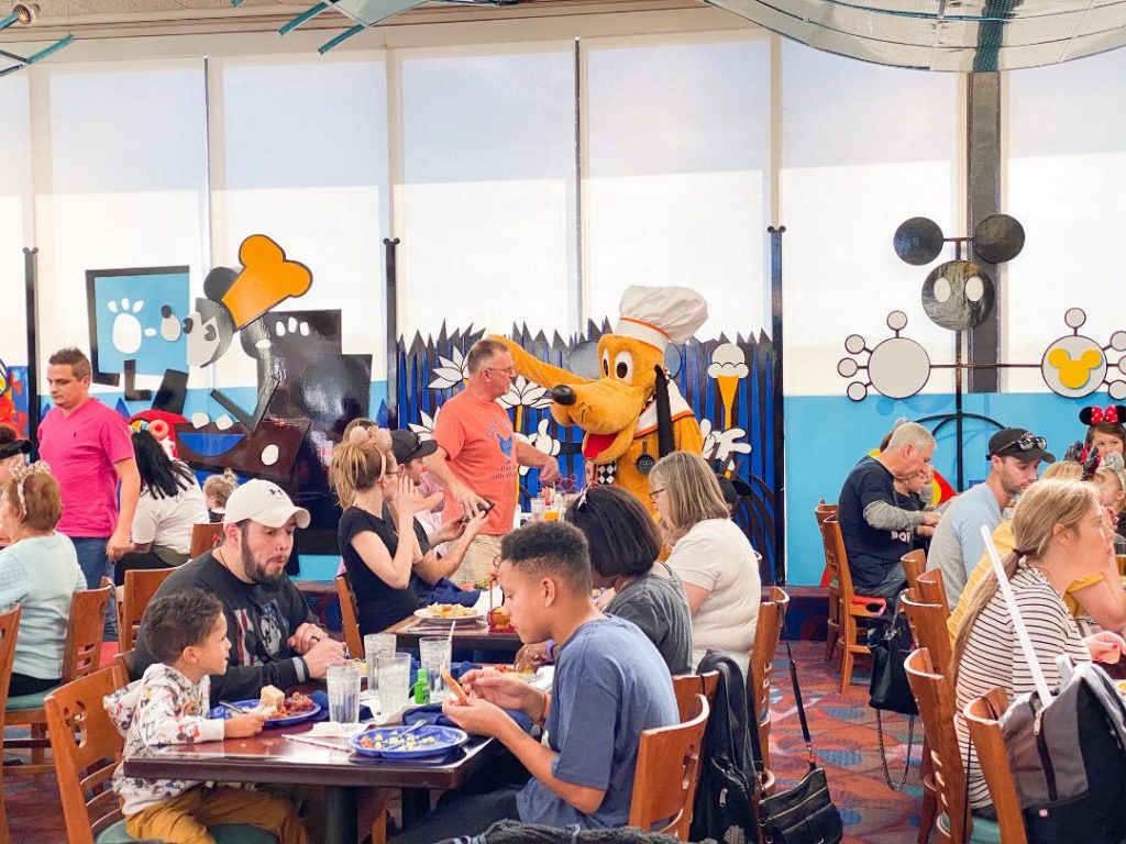 crowd eating a character dining at disney with pluto character