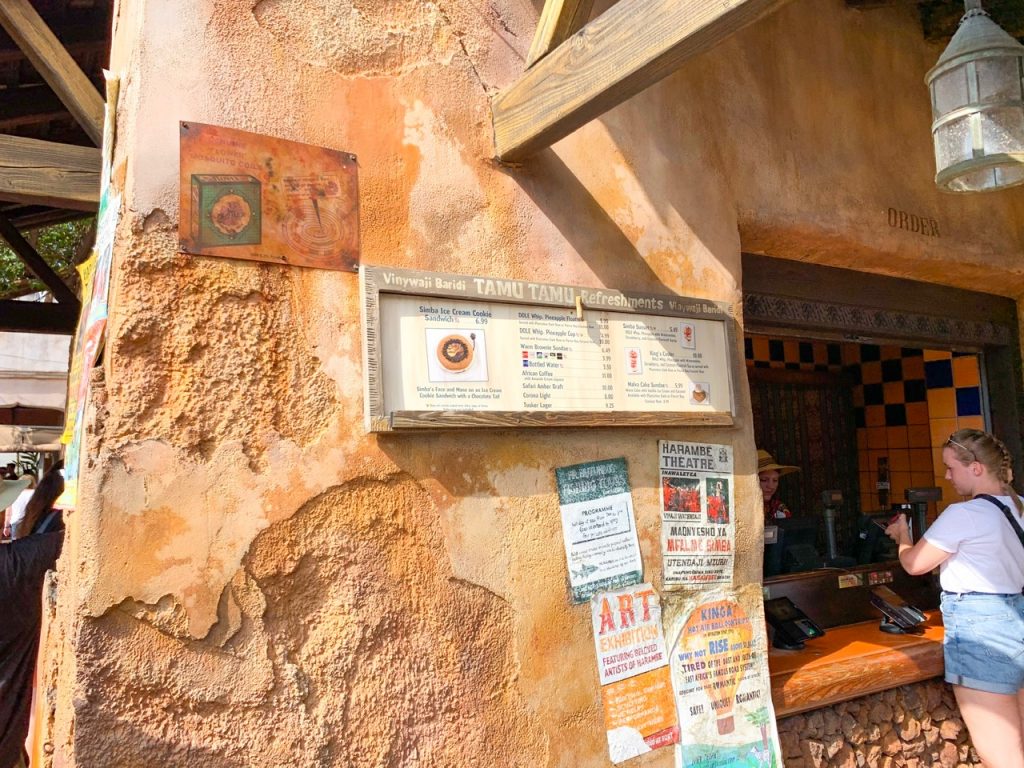 sign at tamu tamu  on clay wall with faded old posters Animal Kingdom quick service