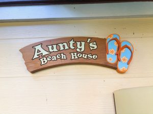 sign for Aunty's Beach House with pair of orange and blue slippers