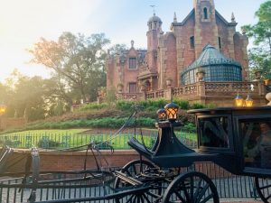 exterior of the Haunted Mansion with a black carriage in front with no horse