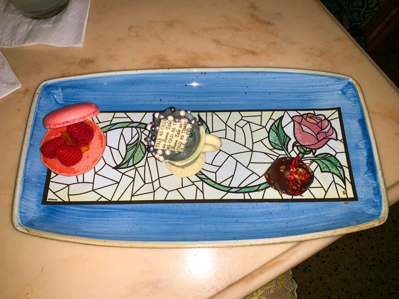 The imitation stain glass rose dessert plate features three desserts at Be Our Guest. With these three desserts, no wonder Be Our Guest is one of Magic Kingdoms best restaurants! 