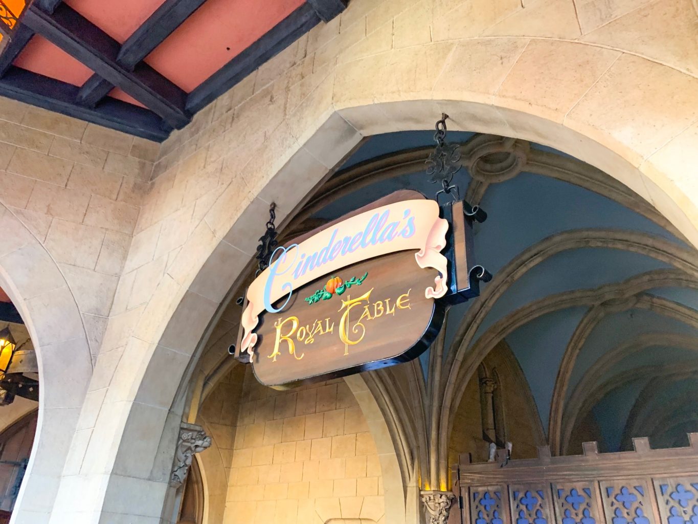 The sign for Cinderella's Royal Table-- which is one of the best restaurants in Magic Kingdom-- hangs under stone archway by the iconic castle.