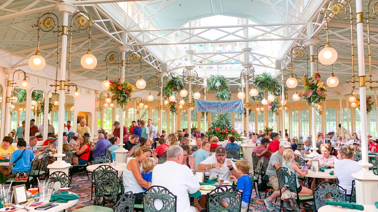 greenhouse-like dining area filled with people Magic Kingdom restaurants