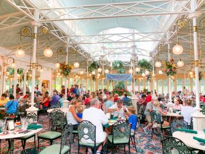 greenhouse-like dining area filled with people Magic Kingdom restaurants