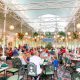 greenhouse-like dining area filled with people Magic Kingdom restaurants