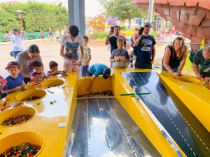 children lining up their lego cars along a bright yellow race track