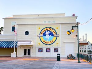 square pale yellow building with logo of two people dancing