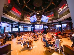 dining area with wooden chairs and a dozen TVs showing sports games