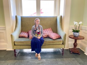 woman in Mickey sweatshirt sitting on vintage-style olive couch