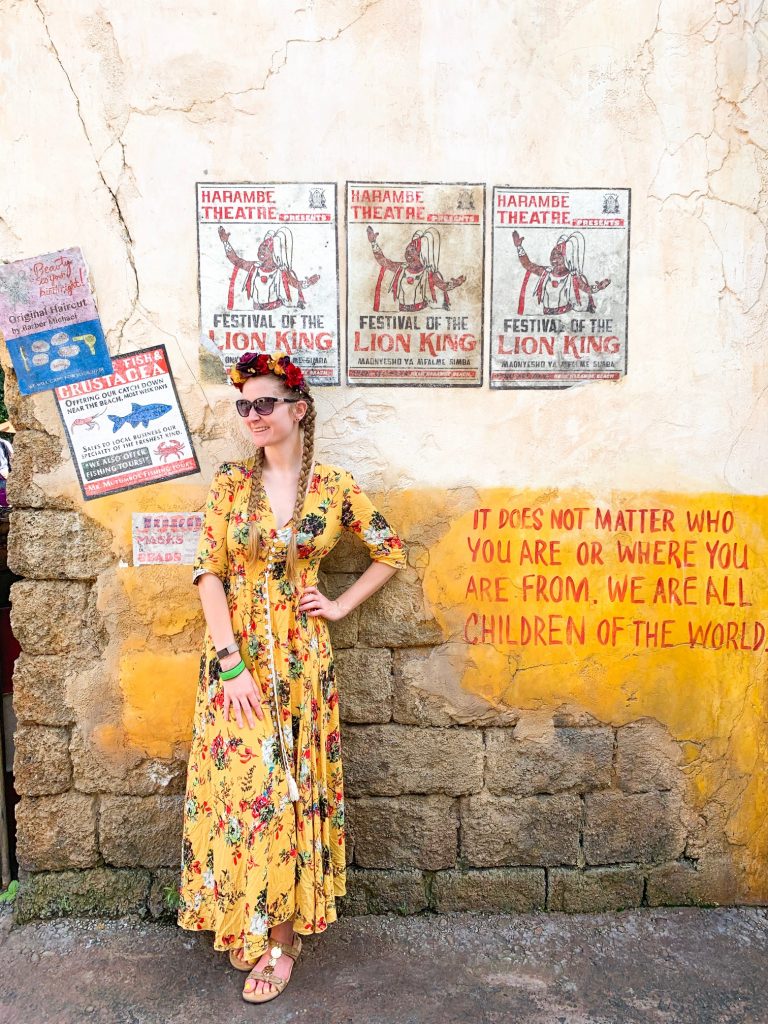 woman in yellow floral dress in front of colorful wall with posters