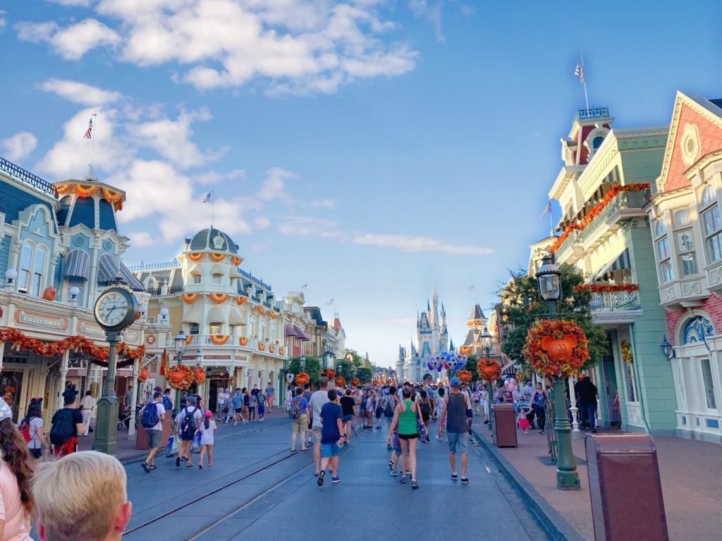 people walking down street in between buildings with Halloween decorations disney on a budget