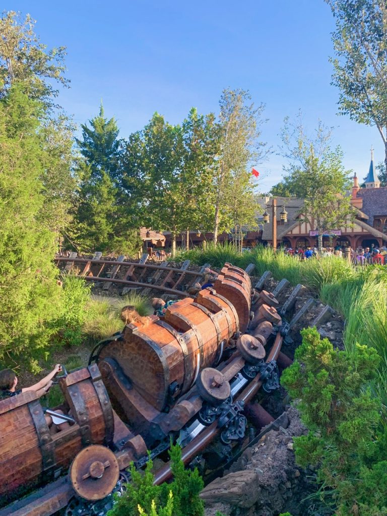 wooden mine carts on a roller coaster track with trees around it 