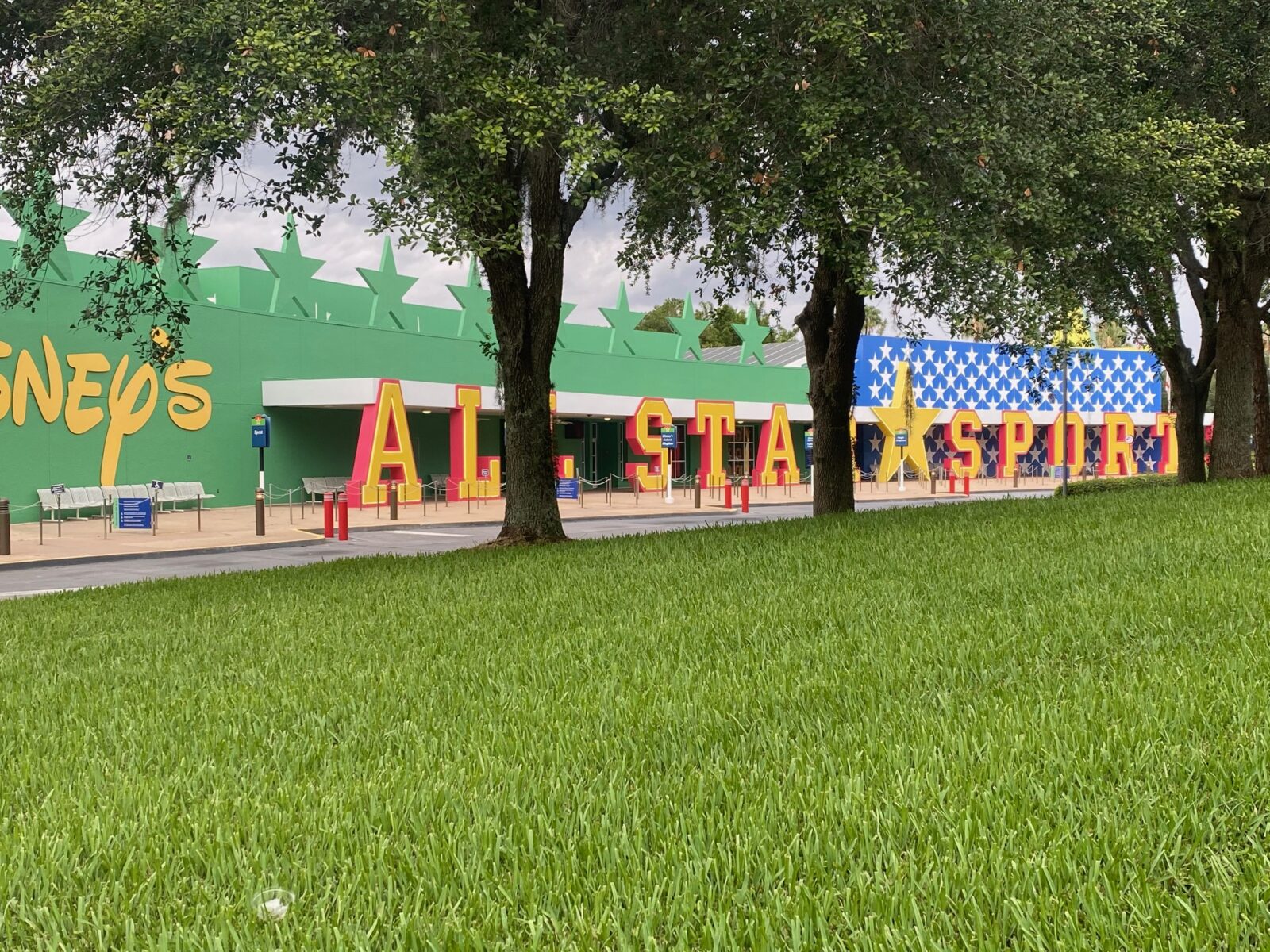 trees and grass in front of colorful hotel sign and entrance for all star sports Disney World resort 