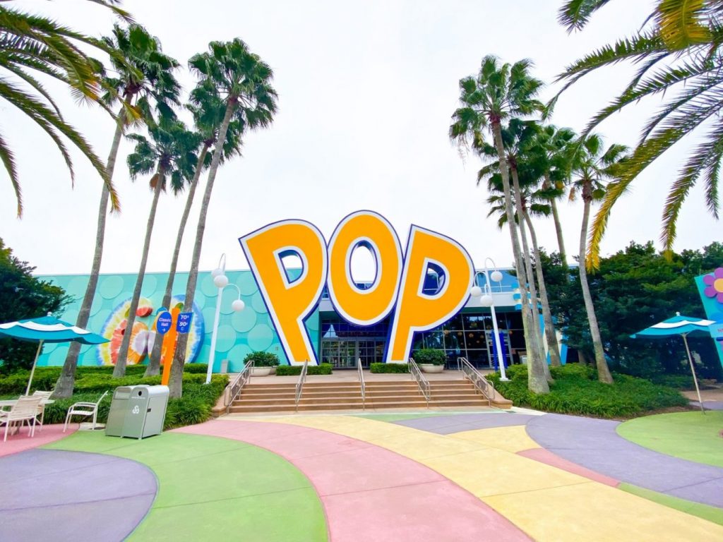 large yellow sign that reads "pop" with colorful walkway and palm trees