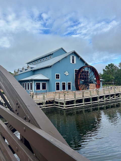 large blue building with water wheel on a river 