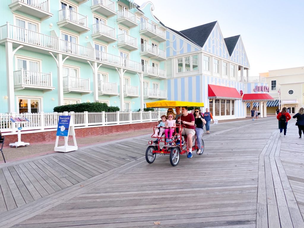 photo of a family on a Surrey bike in front of the Boardwalk Inn; best Disney resort for kids