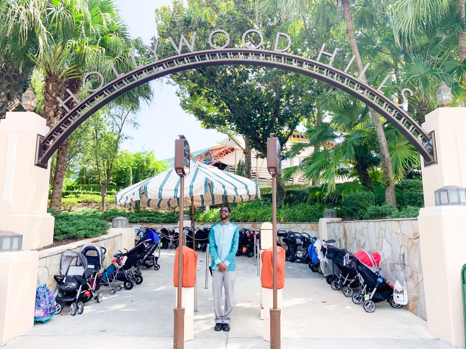 man standing at entrance to outdoor theater will lots of trees and strollers behind him