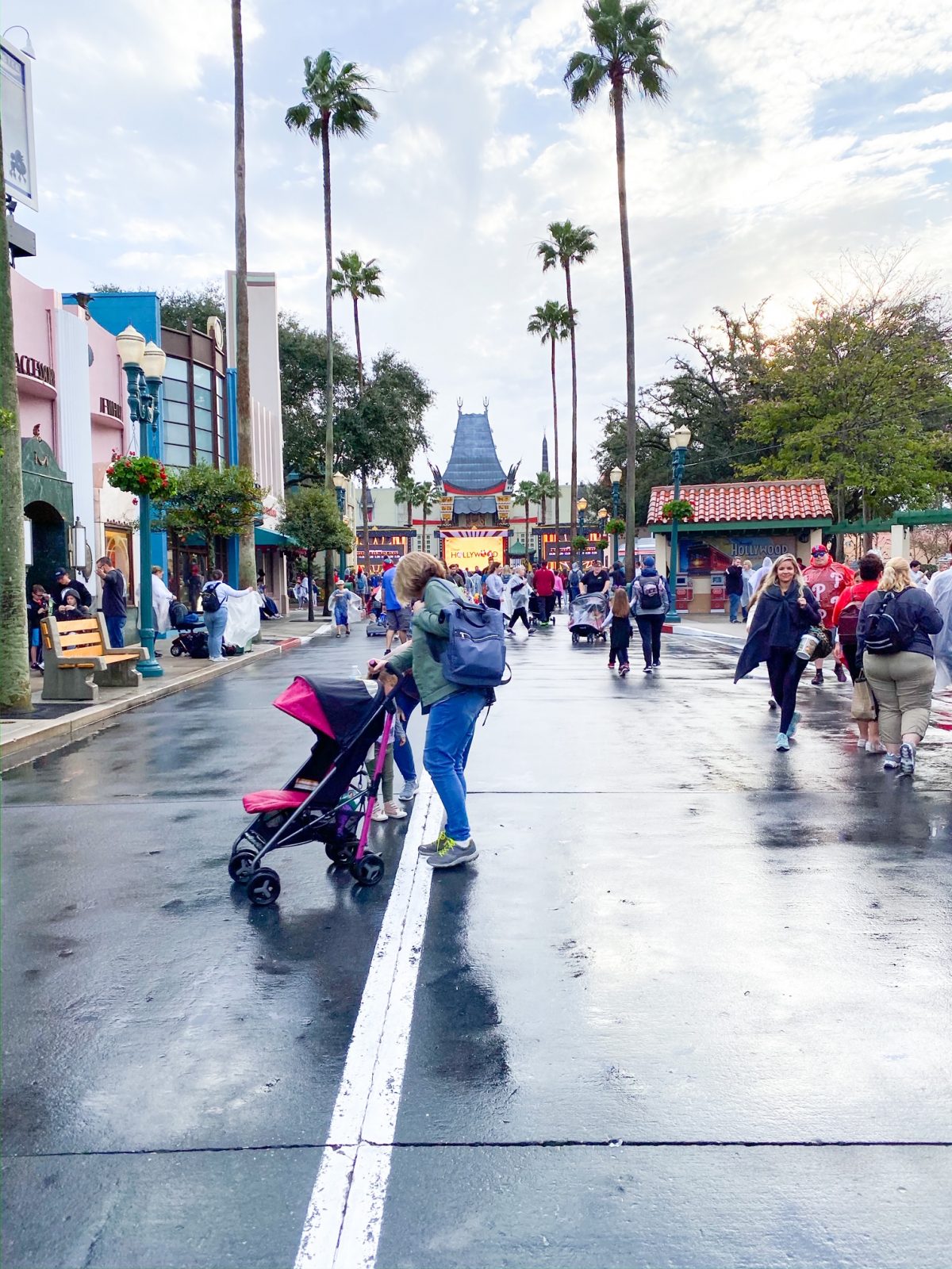 In this photo, a woman pushes a stroller through Hollywood Studios: strollers at Disney help navigate large walking spaces in parks like this one.