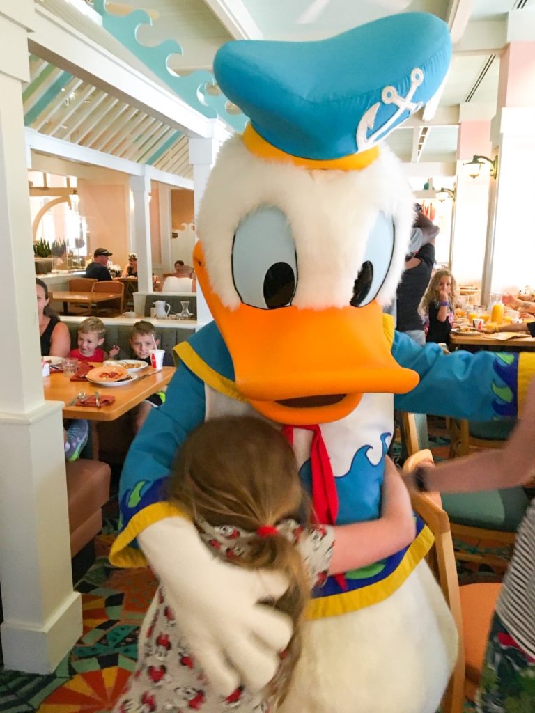 A photo of a little girl cuddling Donald, showing what Disney with toddlers is meant for!