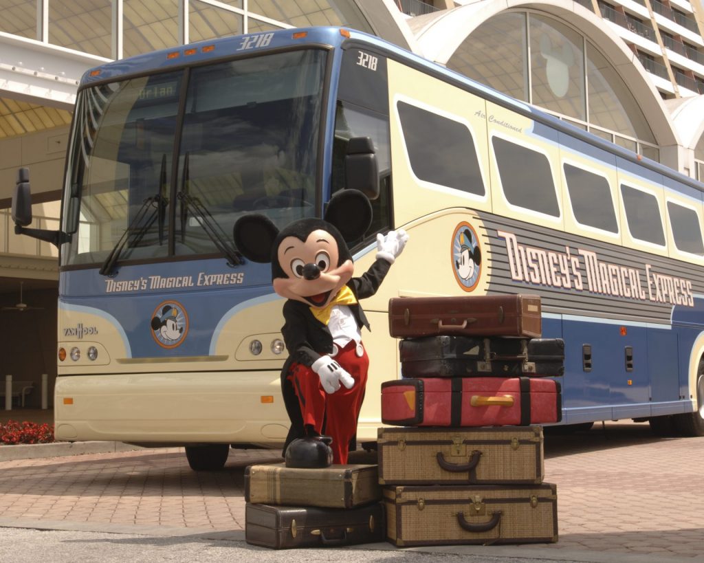 A photo of Mickey Mouse in front of the Magical Express, which makes making Disney with toddlers easier in regards to transportation. 