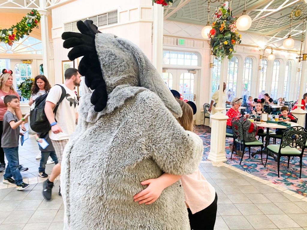 A photo of a child hugging Eyeore at breakfast; these are the Disney with toddlers moments that are worth it!