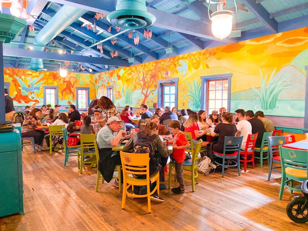 A photo of people eating in a colourful dining area, which makes Disney with Toddlers much more fun-- they love to be engaged with good theming and bright colors! 