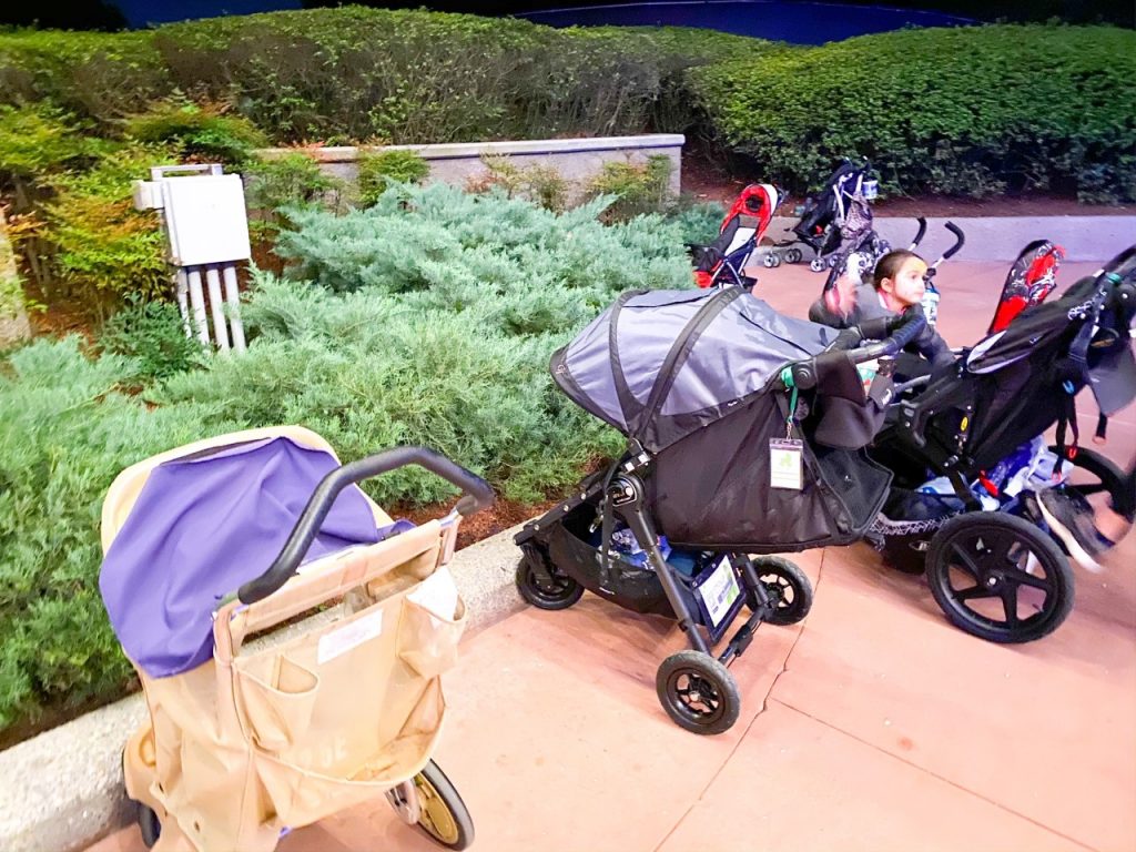A photo of an assortment of different types of strollers parked outside of a ride entrance. Disney with toddlers can be hard to navigate when considering where to park strollers!