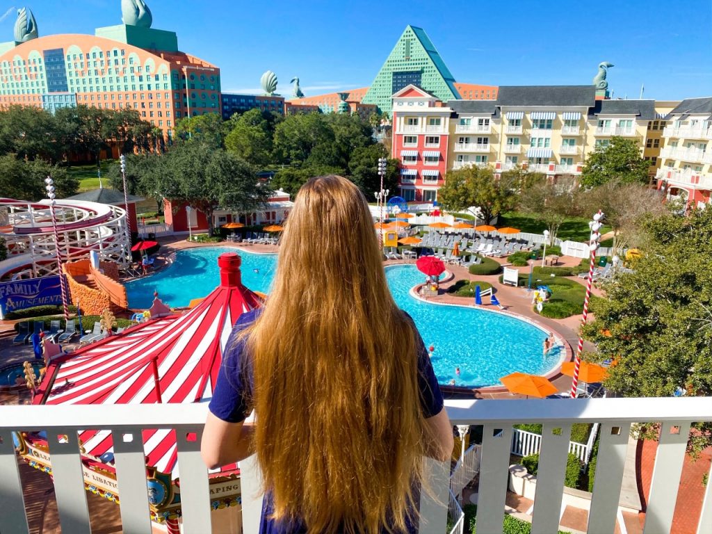 photo of a view from a balcony, overlooking a bright pool and the Swan and Dolphin resorts; how to rent DVC points at Disney Deluxe resort