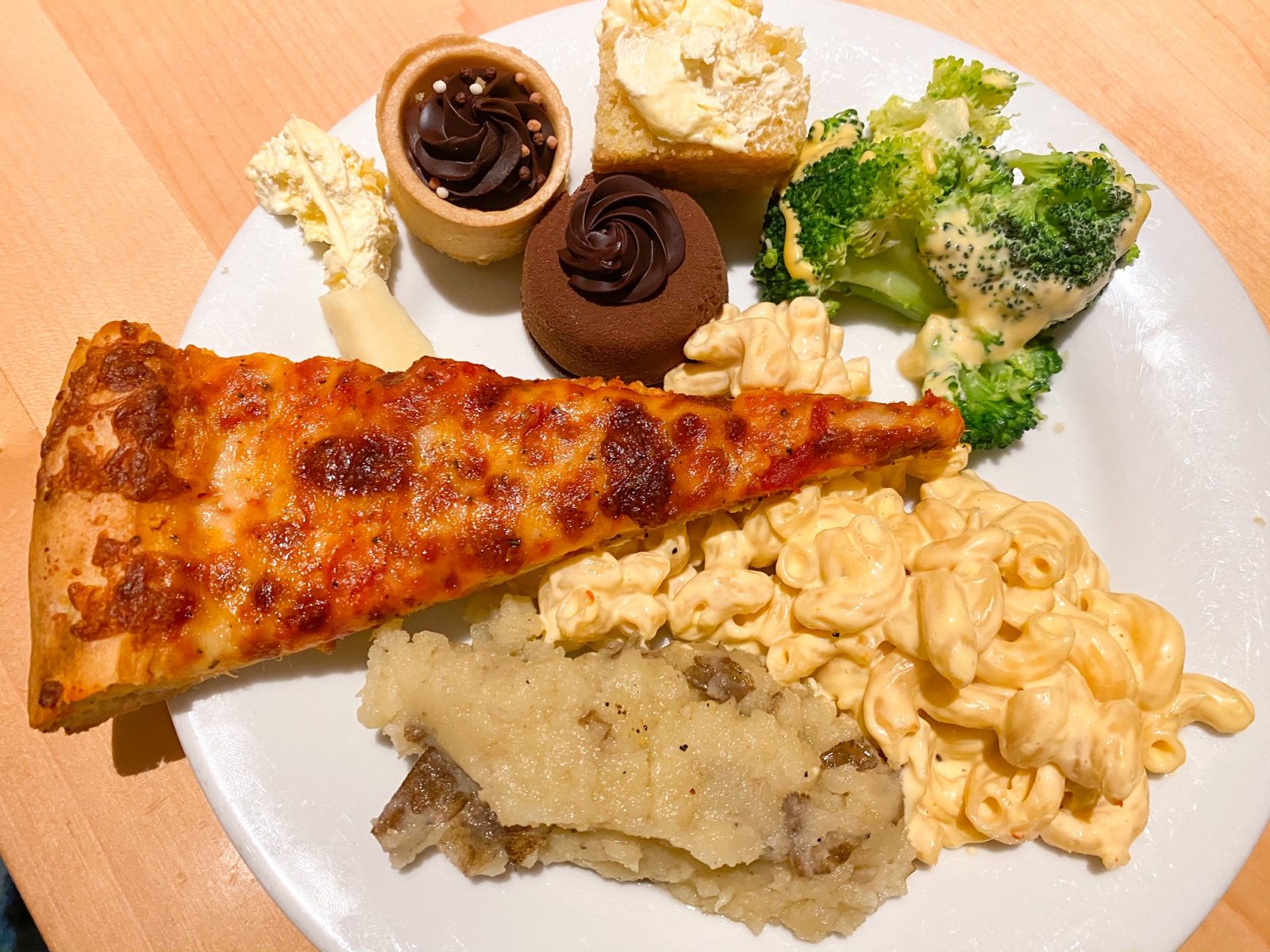 buffet plate with pizza, Mac and cheese, vegetable and dessert at Disney dining plan restaurant