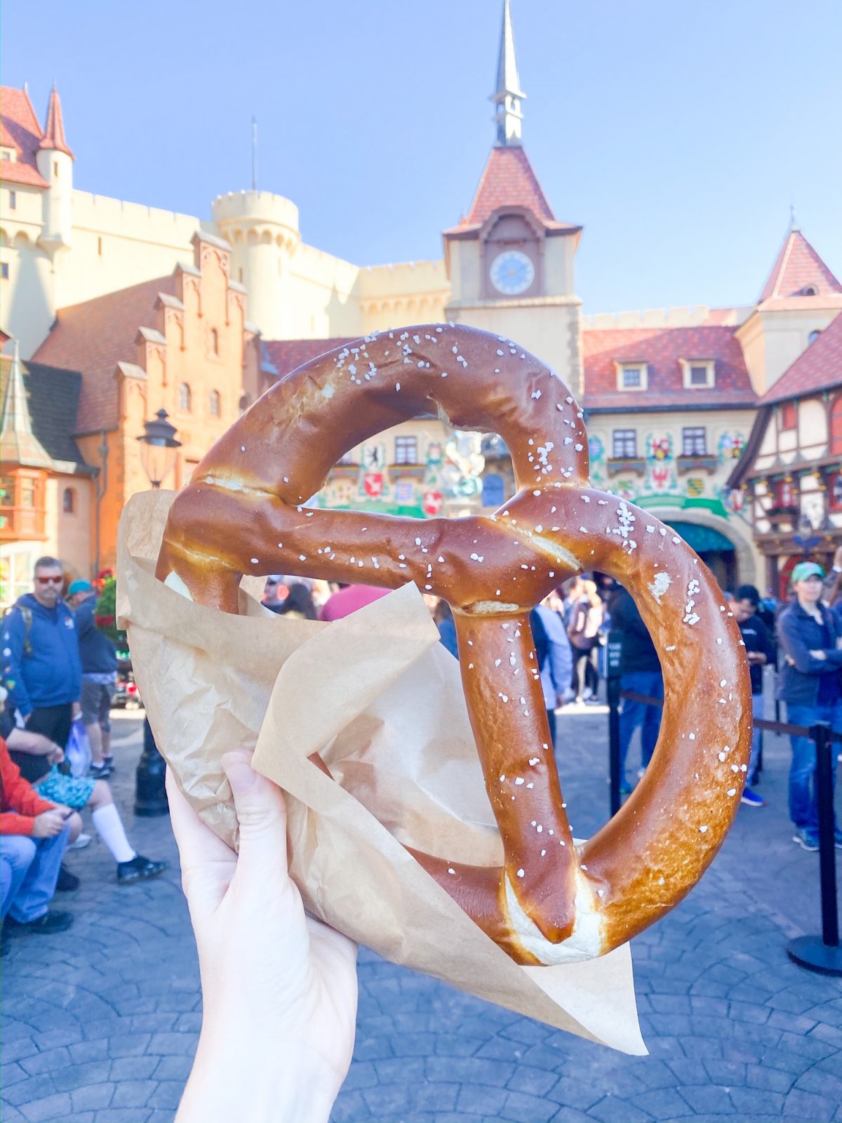 hand holding Giant pretzel in front of German buildings 