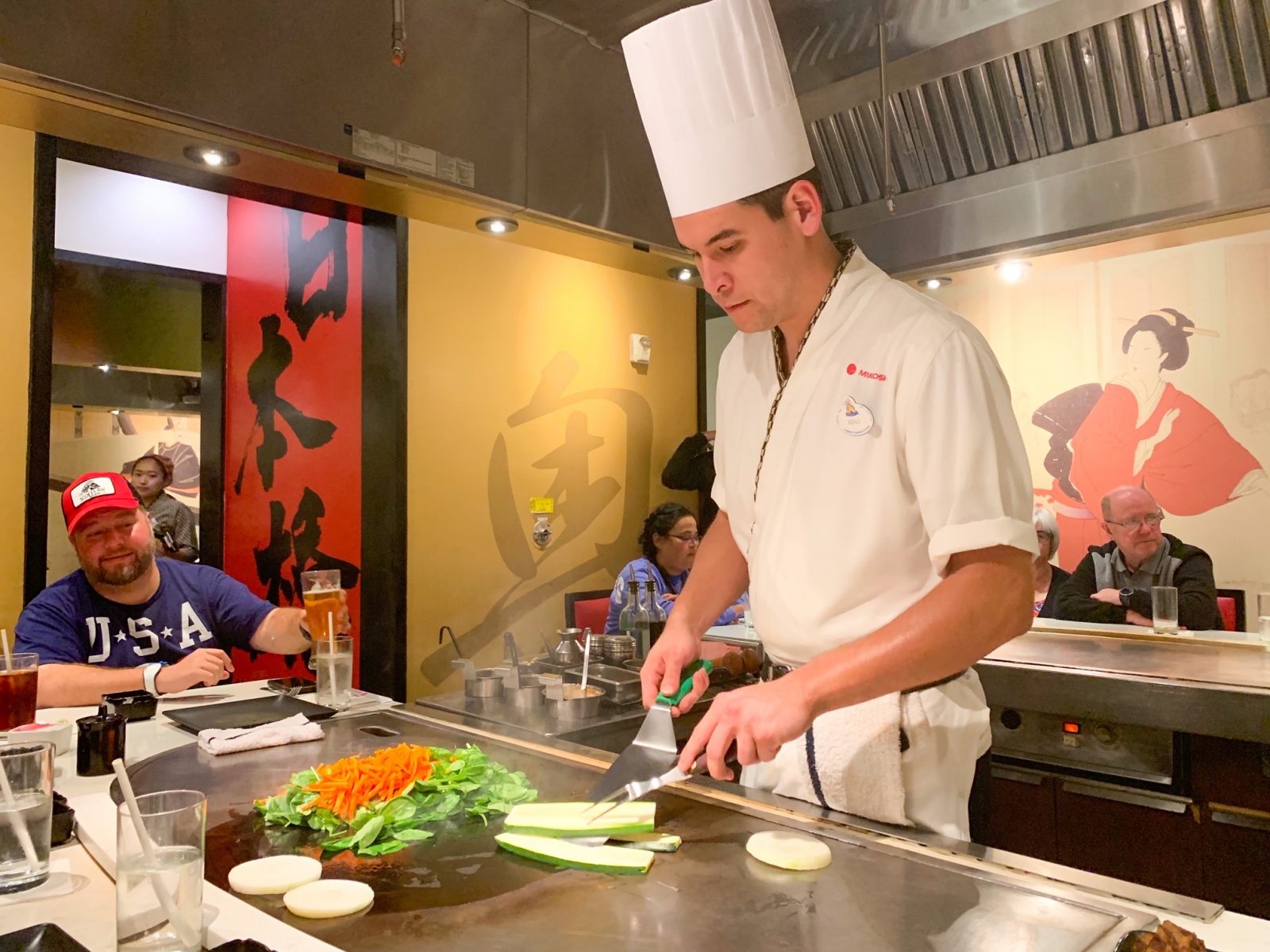 chef cooking vegetables on flat top with people watching at Disney dining plan restaurant 