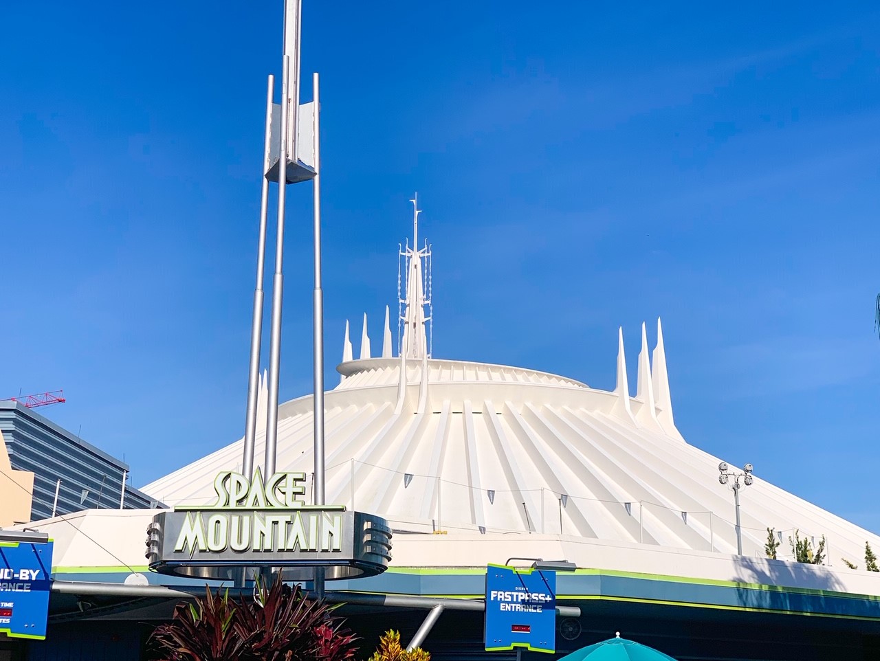 white futuristic building against blue sky with space mountain sign