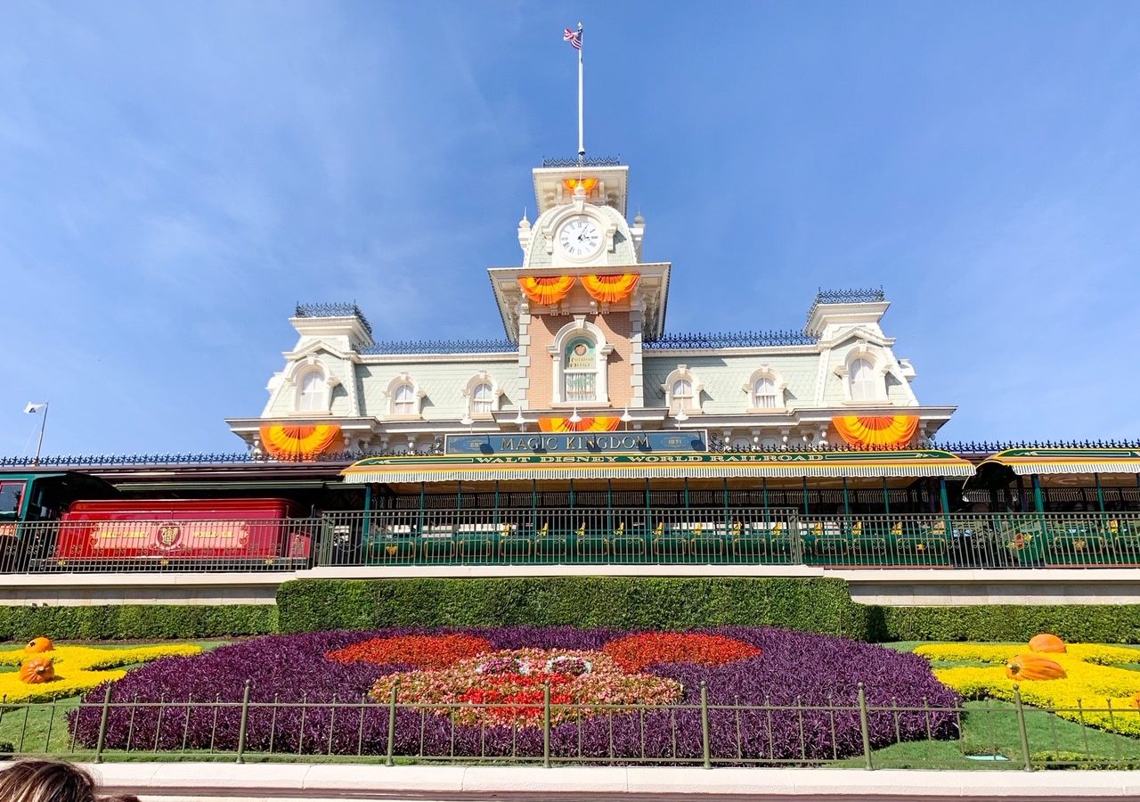 Mickey Mouse made of flowers and white and brick train station with train magic kingdom itinerary stop