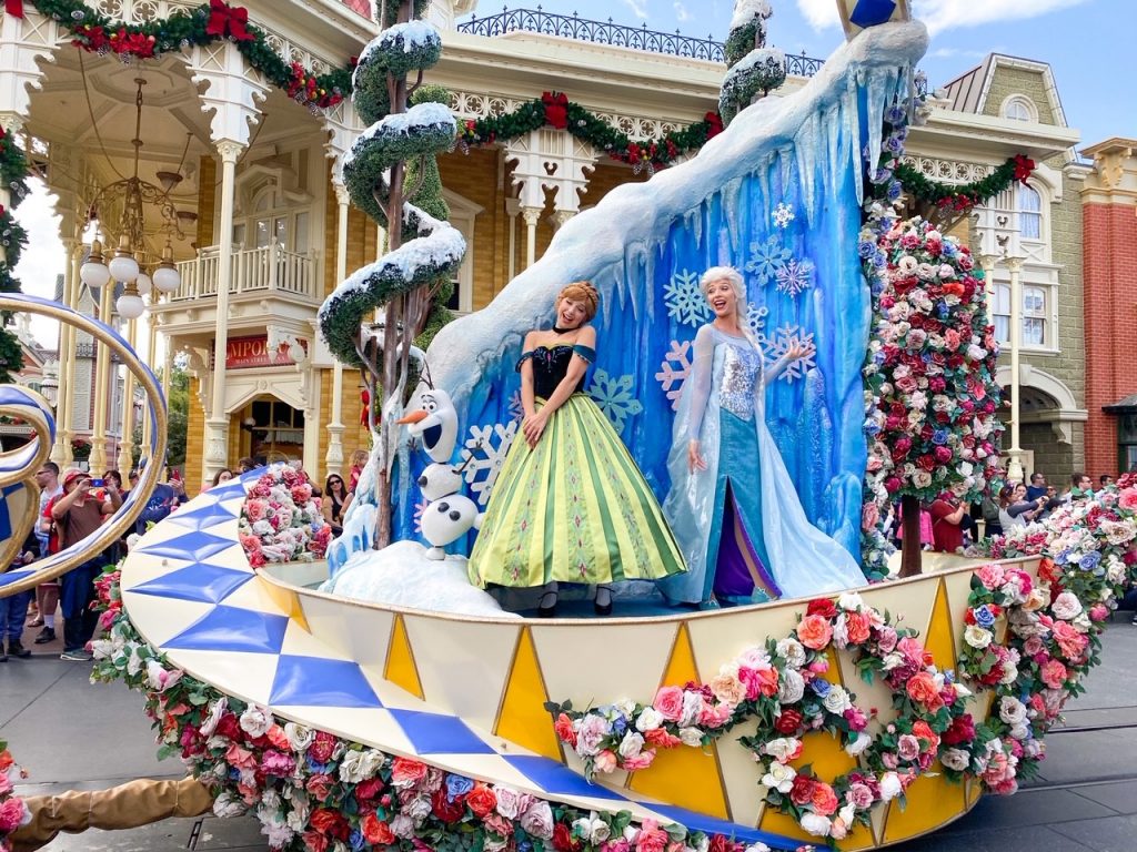 women in princess dresses on parade float with flowers and ice magic kingdom itinerary
