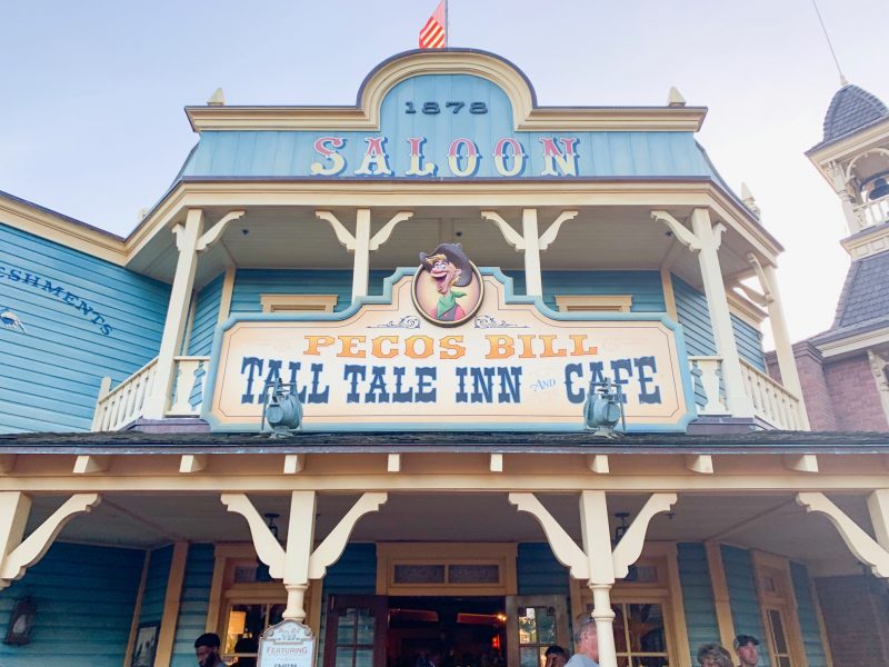 blue and cream saloon style building with sign for pesos bill magic kingdom itinerary