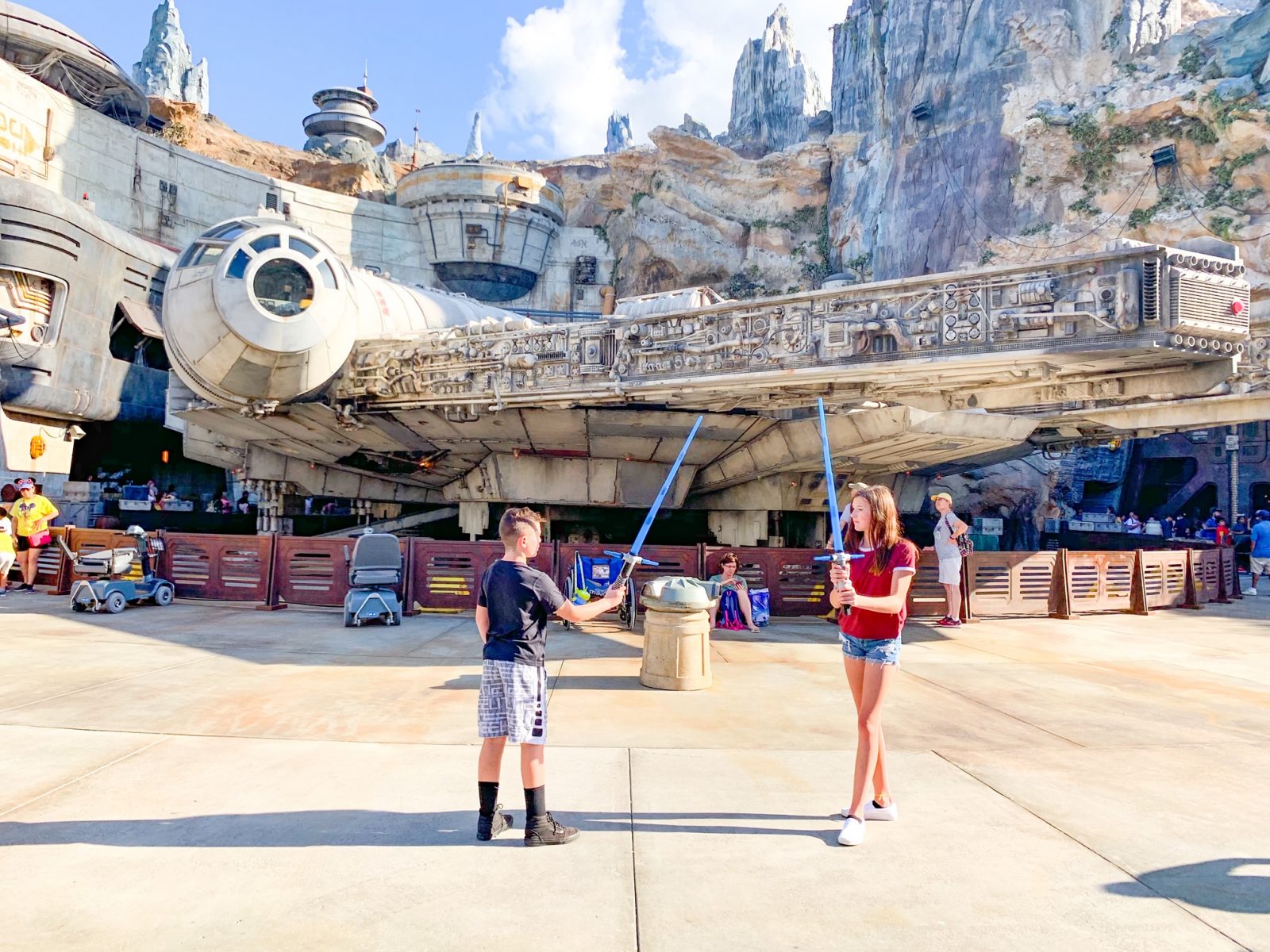 teens posing with lightsabers in front of the Millennium Falcon