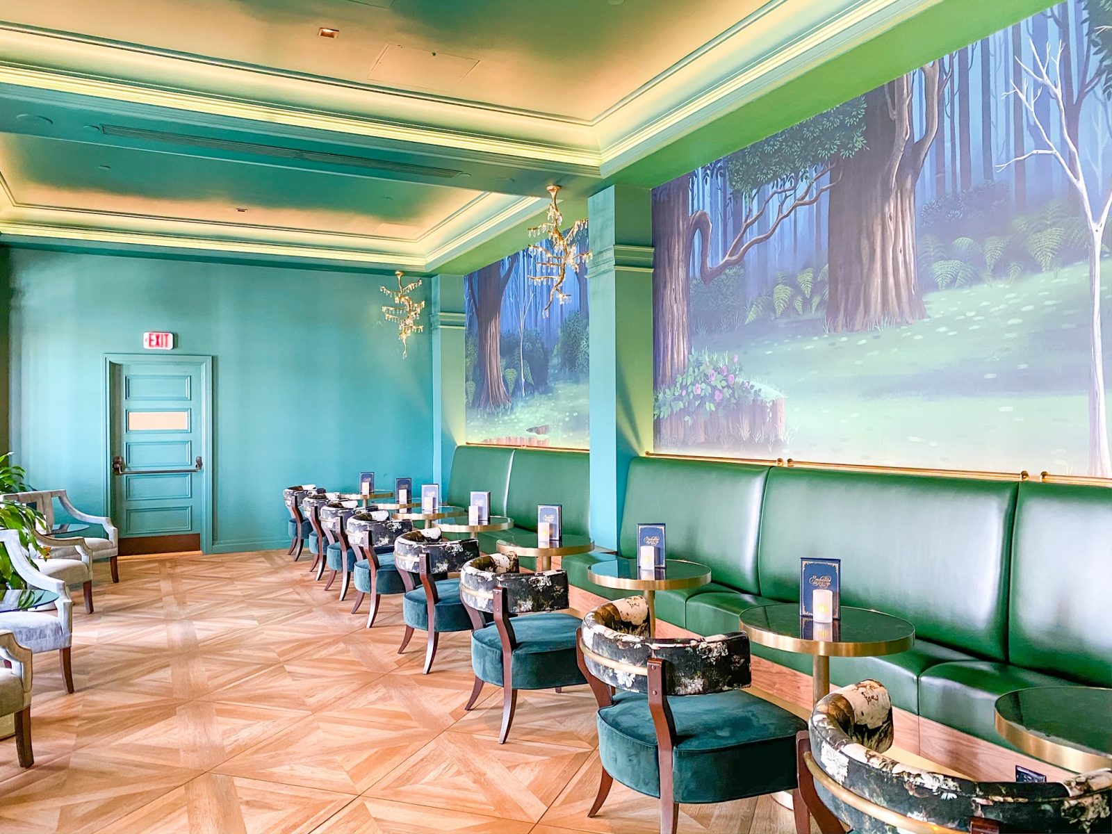 green elegant lounge with painting of a forest on the wall with chairs and tables at grand Floridian Disney monorail resort 