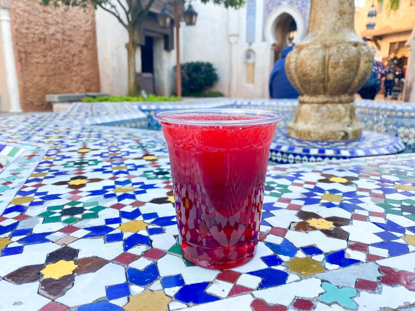one of the best drinks at Epcot Habibi in red on a tiled fountain surface