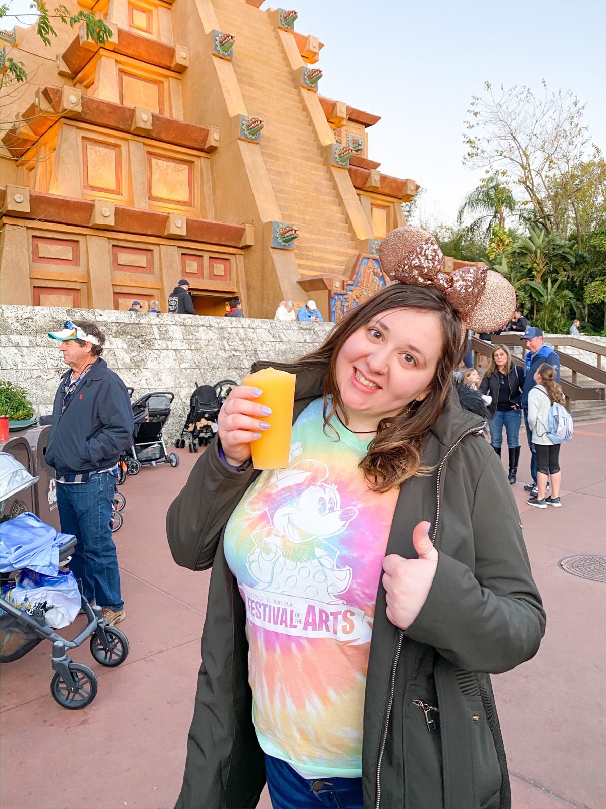 woman holding a yellow drink in epcot mexico while drinking around the world at disney