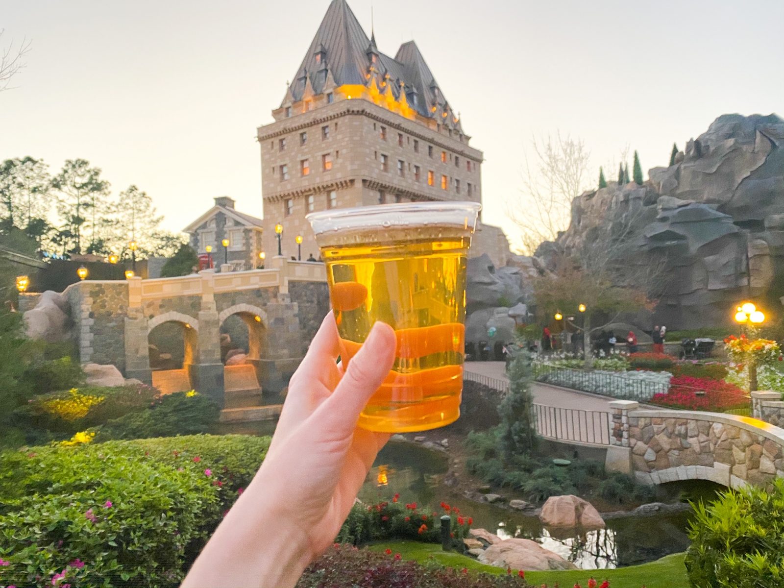 womans hand holding Moosehead Beer around the world in Epcot with sunset in the sky